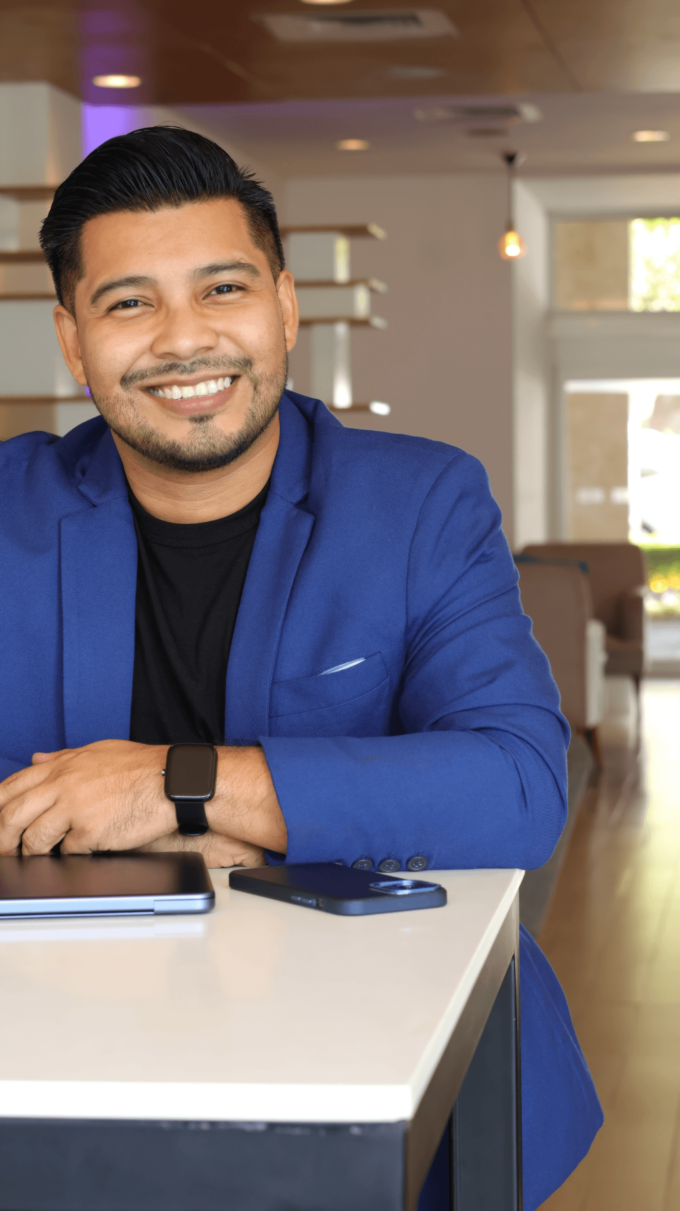 Samuel García sonriendo, apoyado en una mesa de trabajo con su tableta y su teléfono